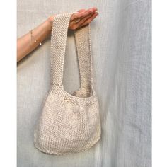 a hand holding a white knitted purse