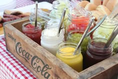 a wooden box filled with lots of different types of drinks and condiments on top of a checkered table cloth