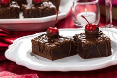 two pieces of chocolate cake with cherries on top