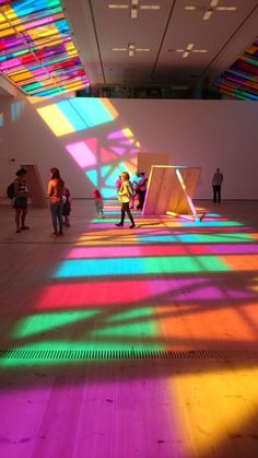 people are standing in an art gallery with brightly colored lights on the walls and floor