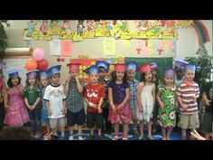 a group of children standing next to each other in front of a wall with balloons on it