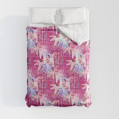 a bed with pink and blue leaves on it, next to a white pillow case