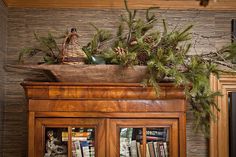 an image of a fireplace with pine cones on top and evergreen branches in the middle