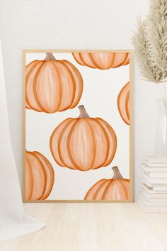 an orange pumpkin painting on a white wall next to a vase with dried flowers in it