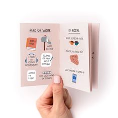 a hand holding an open book with stickers on the front and back of it