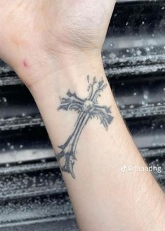 a person with a cross tattoo on their wrist