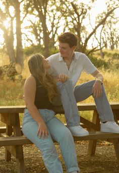 a man and woman are sitting on a picnic table with their hands around each other