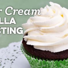 a cupcake with white frosting sitting on top of a green paper doily