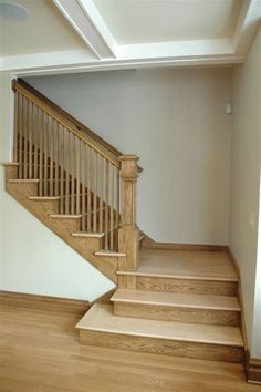 an empty room with wooden stairs and hard wood flooring on either side of the staircase