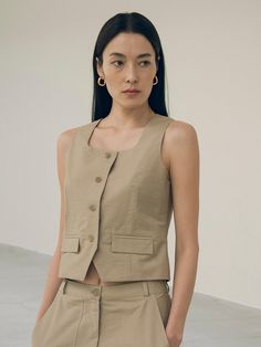 This is a refined and minimal vest by Siyazu that is made out of high quality and sturdy material. With classic mood of the design and feminine look, you can style it for your refined and casual daily outfit.- Set up with matching pants- Bio processed fabric with soft touch- Curved square neckline- Ox horn buttons detail Classic Cotton Tank Top For Work, Versatile Fitted Beige Tank Top, Chic Vest With Pockets, Classic Beige Vest Top, Classic Beige Vest For Summer, Classic Fitted Beige Tank Top, Fall Fitted Vest For Everyday, Elegant Beige Vest For Layering, Versatile Cotton Vest For Spring