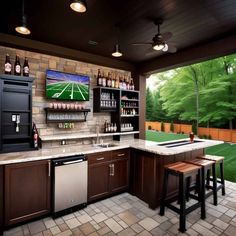 an outdoor bar with two stools in front of it and a television on the wall