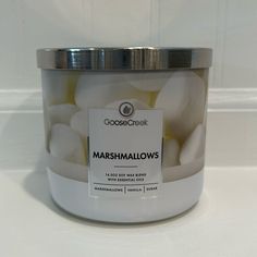 a white jar filled with marshmallows sitting on top of a table next to a wall