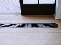 a floor drain cover on the ground in front of a door with an open window