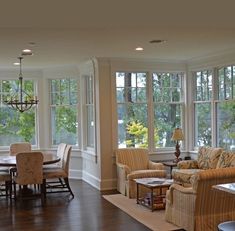 a living room filled with furniture and lots of windows next to a wooden floored floor