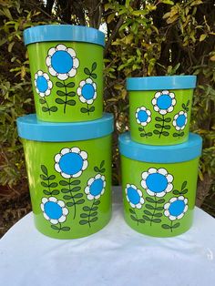 four green and blue flower pots sitting on top of a white table