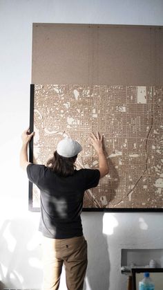 a person standing in front of a wall with a map hanging on it's side