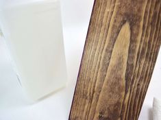 a piece of wood sitting next to a bottle of liquid on a white table top