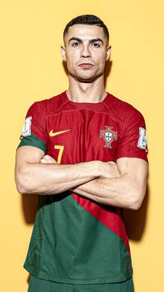 a man in a red and green shirt is posing for a photo with his arms crossed