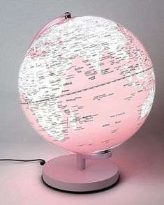 a pink and white illuminated globe on a stand with plugged in wires attached to it