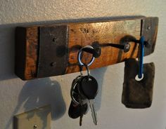 two keys are hanging on a wooden key rack with hooks and locks attached to it