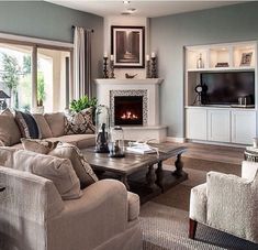 a living room filled with furniture and a fire place in the middle of it's wall