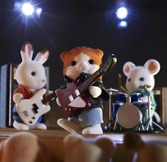 three toy mice playing music instruments on stage