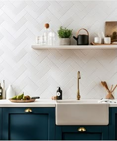 a kitchen with blue cabinets and white tile backsplashing, gold faucets