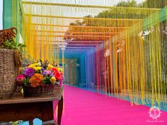 a table with flowers on it in front of some colorful walls and hanging strings over the tables