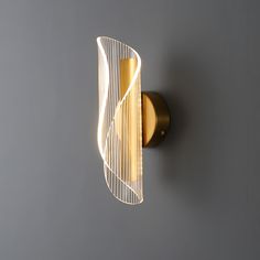 a wall mounted light on the side of a gray wall with a curved glass shade