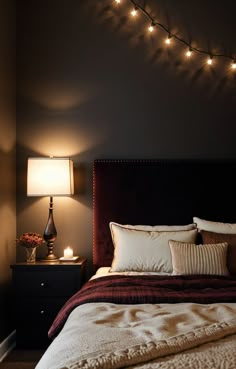 a bedroom with lights strung over the headboard and pillows on the bedspread