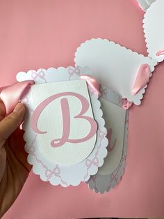 someone is holding up a card with the letter b in pink and white on it