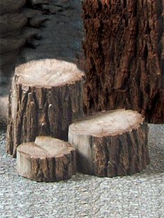 three pieces of wood sitting next to each other on top of a cement ground with rocks in the background