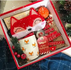 a christmas gift box filled with coffee mugs and other holiday items, including a fox ornament