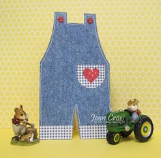 two small toy animals sitting on top of a table next to a pair of overalls