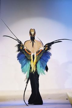 a mannequin with colorful wings on it's head and back, standing in front of a white background