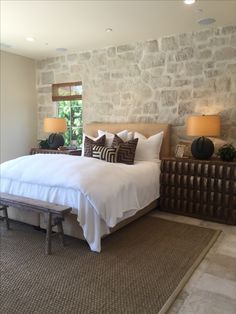 a bedroom with stone walls and white bedding