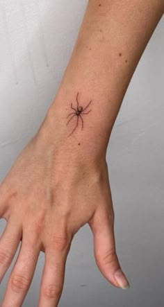 a person's hand with a small spider tattoo on their left wrist and the other arm