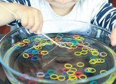 a little boy that is holding a toothpick in some kind of bowl with rings on it