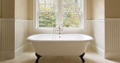 a white bath tub sitting under a window in a bathroom