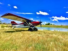 an airplane is parked in the grass near a body of water