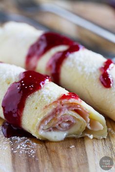 two crepes covered in jam sitting on top of a wooden cutting board