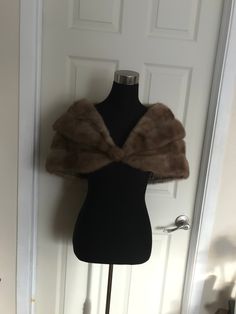 a mannequin with a fur stole on it's head in front of a door