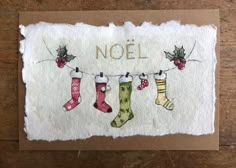 a card with stockings hanging from a clothes line and the words noel written on it