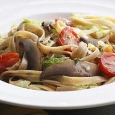 a white plate topped with pasta covered in mushrooms and vegtables on top of it