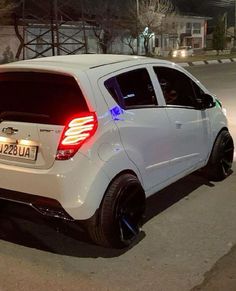 the rear end of a white car parked on the side of the road at night