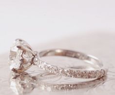 two wedding rings sitting on top of each other with one diamond in it's center