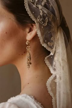 a woman wearing a veil and gold earrings