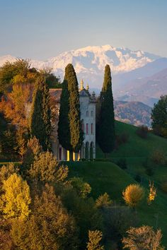 an old house with trees and mountains in the background