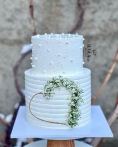 a white wedding cake with greenery on top