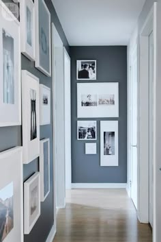 an empty hallway with pictures on the wall and wood flooring in front of it